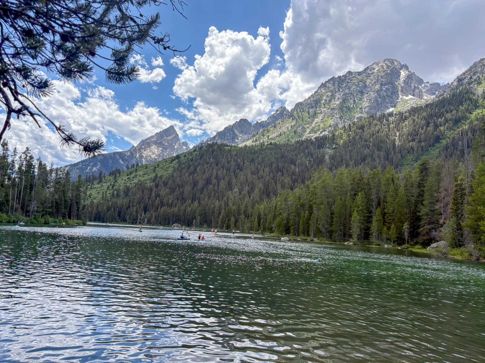 OFY campers paddleboarding on a mountain lake below the Tetons